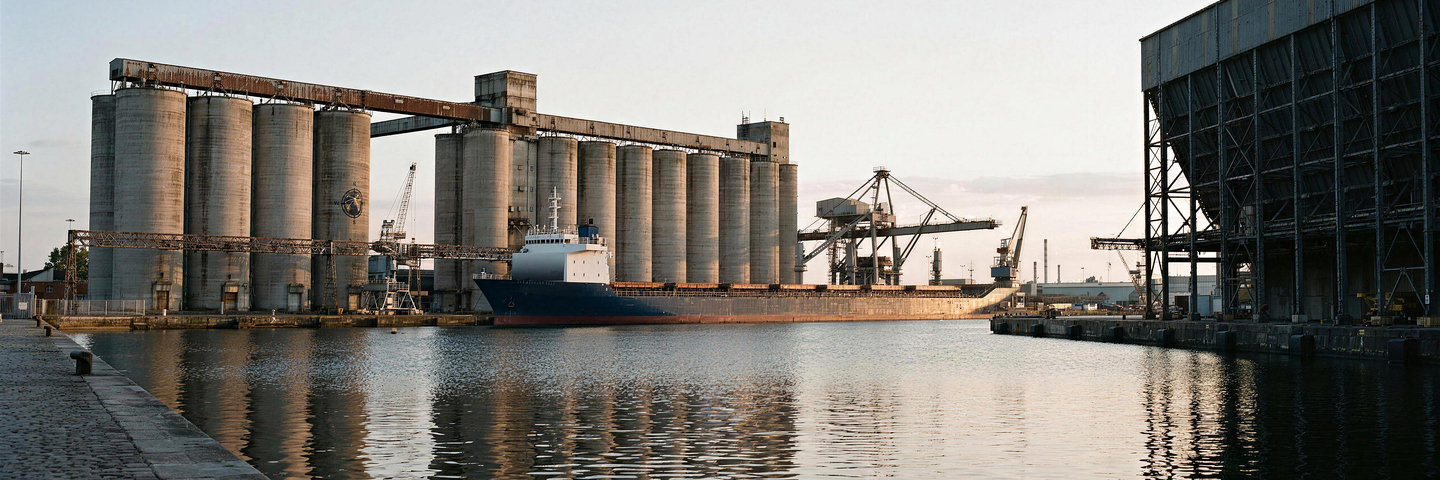 Silos de hormigón y un buque de carga atracado en un muelle al amanecer